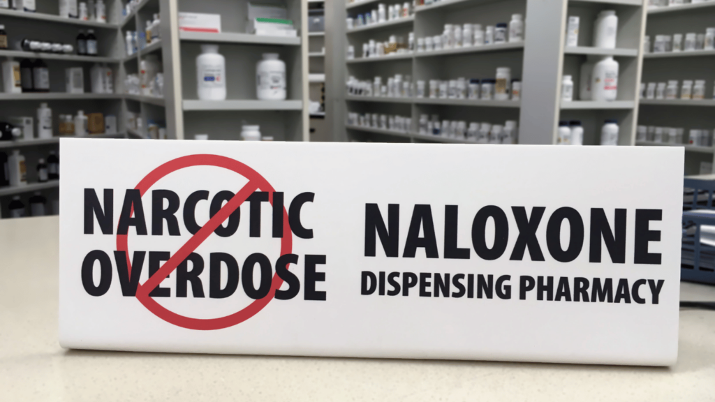 Sign in a pharmacy reading "Naloxone Dispensing Pharmacy," promoting access to opioid overdose reversal medication for fentanyl