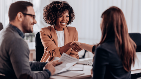Confident woman in a job interview smiling and shaking hands with an employer, representing career success and recovery support with Suboxone treatment
