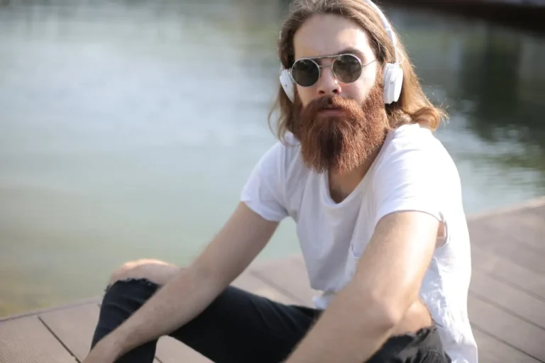 man-listening-to-music-by-the-water-with-sunglasses-on