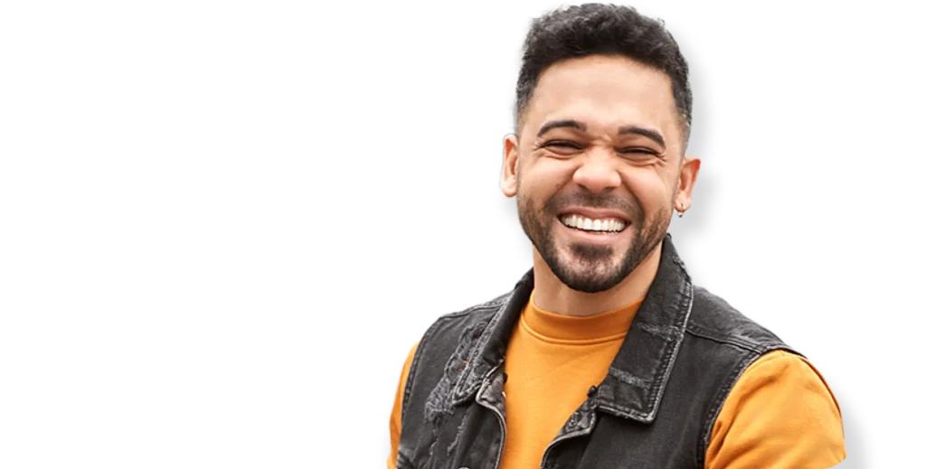 Happy young man smiling confidently after weight loss success, wearing orange shirt and denim vest