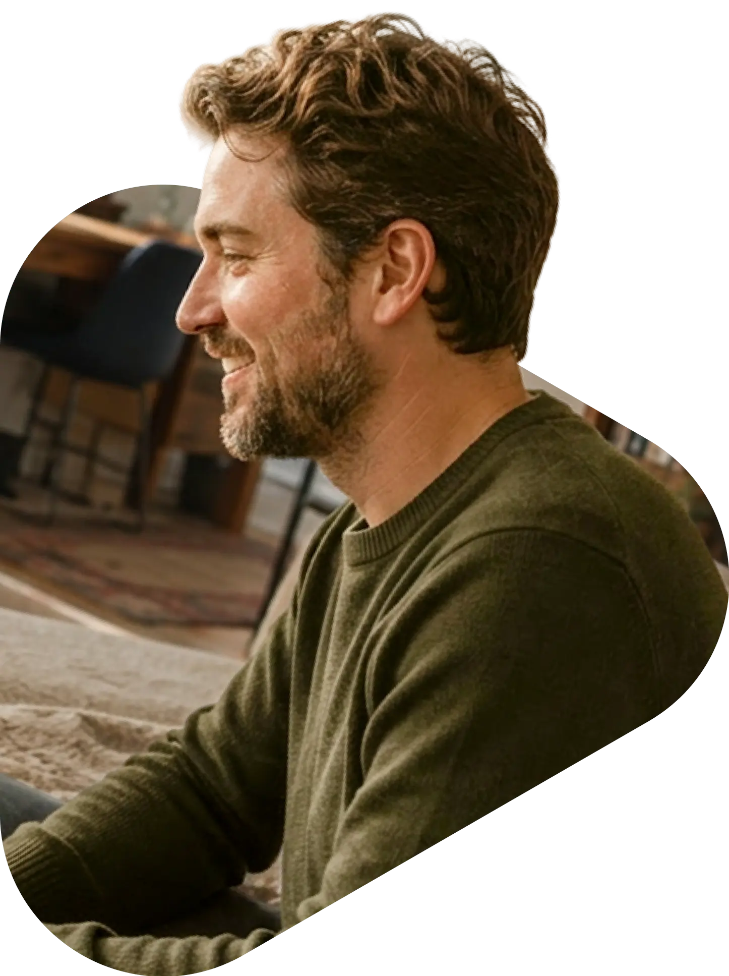 Smiling man with beard in green sweater participating in a QuickMD community peer support group session indoors.
