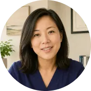 QuickMD female telehealth doctor in navy scrubs smiling in a professional medical office setting