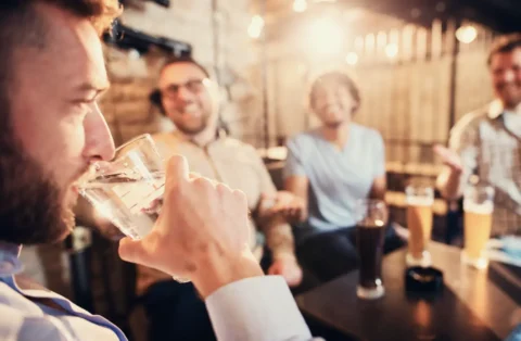 man-drinking-water-near-friends-having-beer