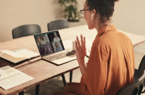 woman-on-computer-in-meeting-with-many-people